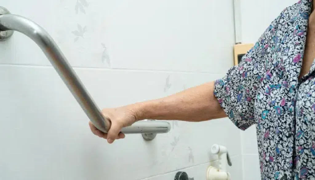 Hand holding a bathroom grab bar for support.