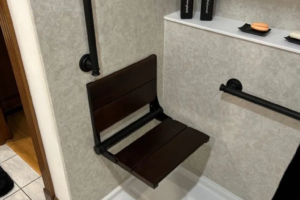 Accessible shower with foldable seat and grab bars.