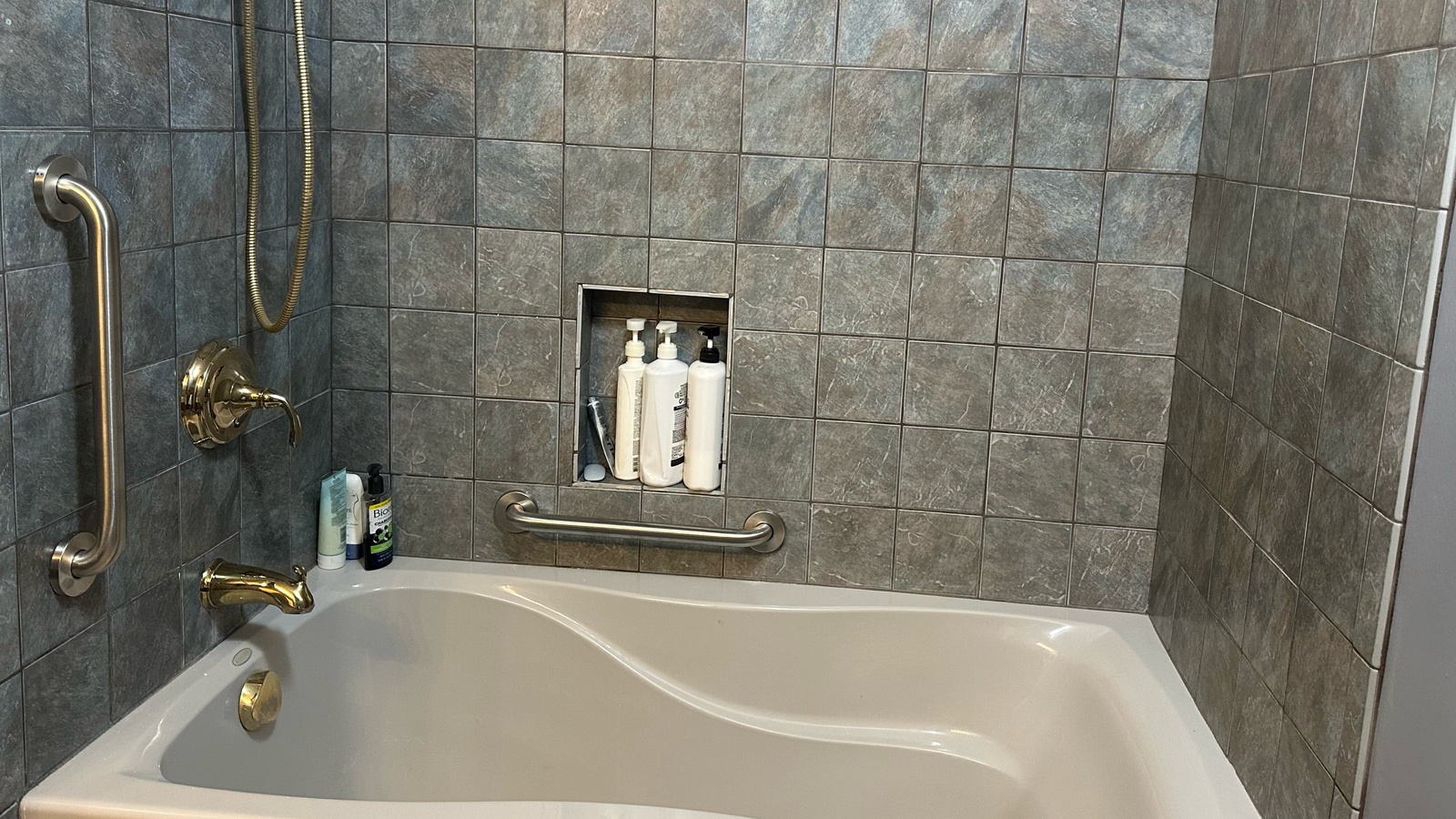 Modern bathroom with a tub and toiletries shelf.