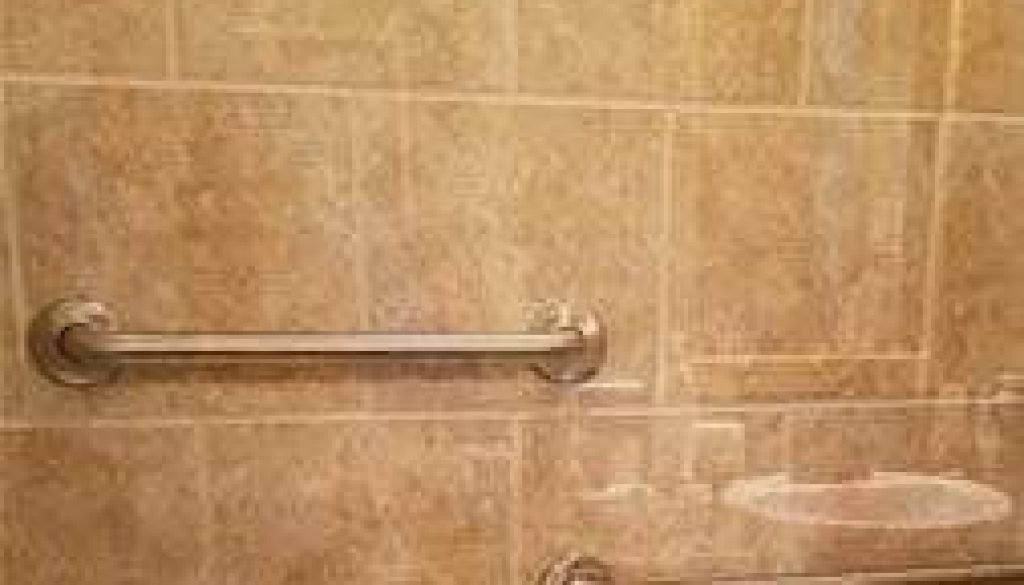 Bathroom wall with grab bars and light reflection.