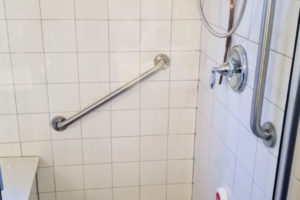 Two Grab Bars Installed In Tiled Walk In Shower With Bench