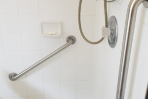 Two Grab Bars Installed On White Tile Shower With Shower Chair
