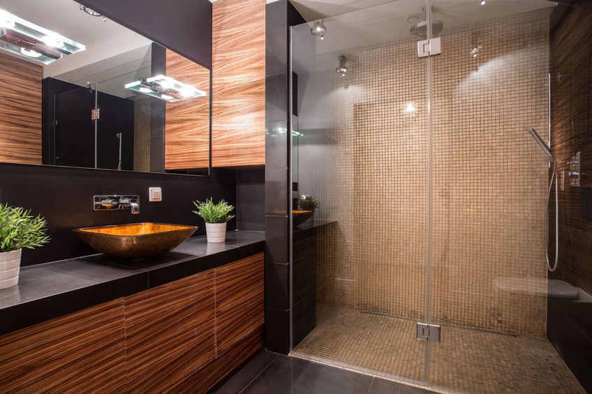 Modern bathroom with wooden accents and glass shower.